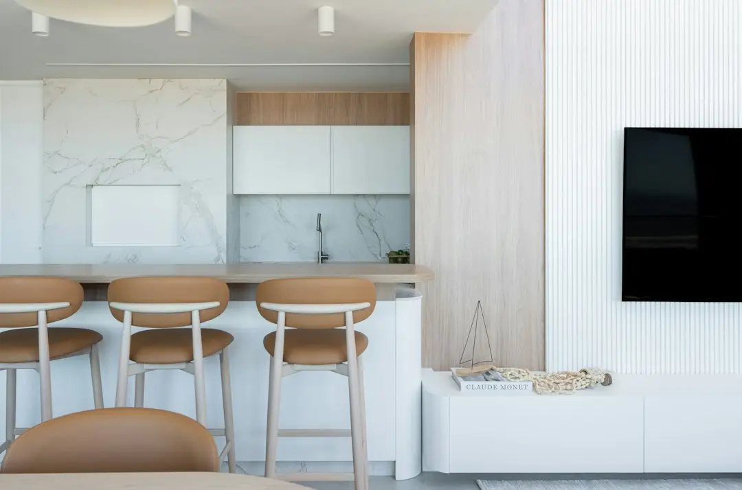 A switched-off TV mounted on the wall of a modern open-plan kitchen.