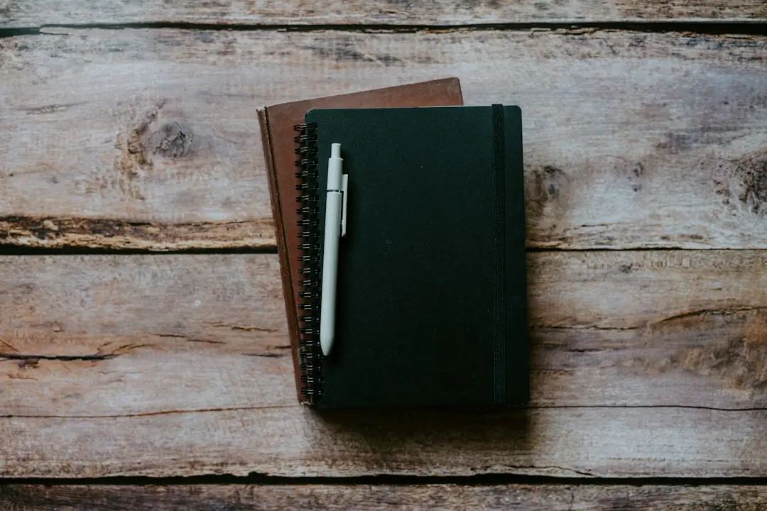 A notebook and a pen on a wooden table.