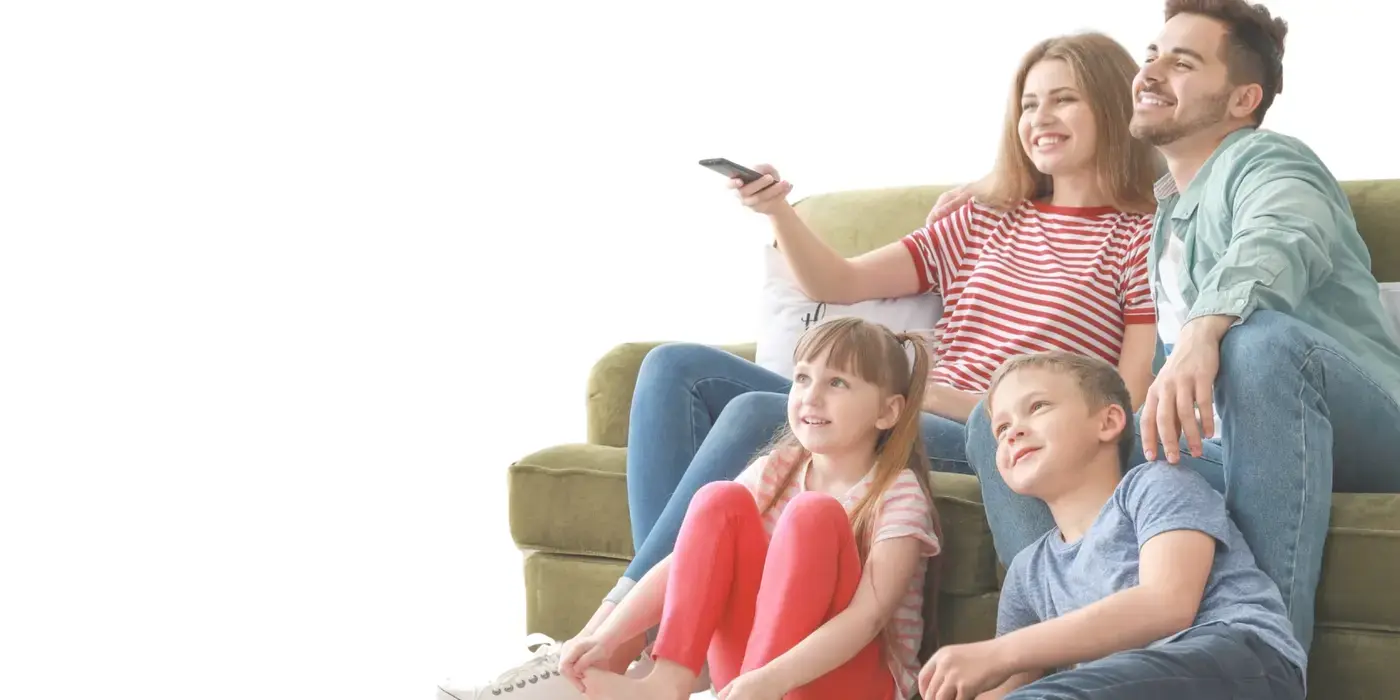 A family watching TV on a sofa, the mother holding the remote